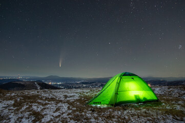 Winter tent in the mountains against the background of stars and comets