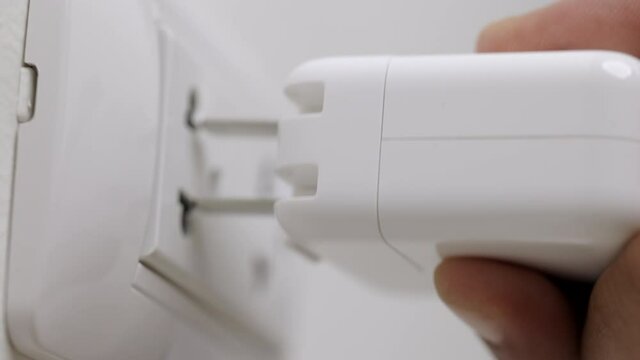 Close up male hand put on the Electric adapter smartphone or laptop plug. Electrical wires and power strips in the house