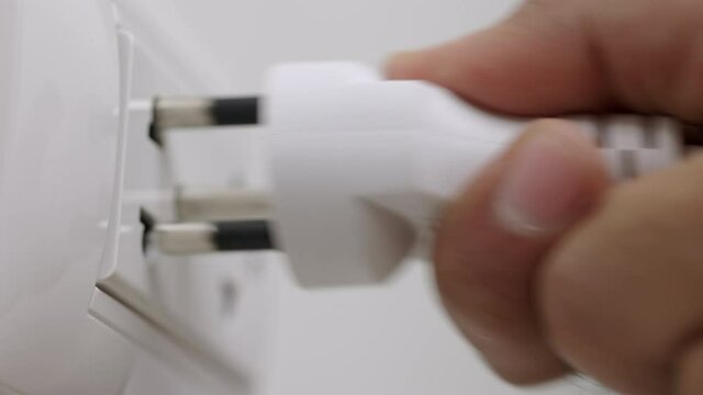 Hand remove Electric plug on socket. Electrical equipment, electrical wires and power strips in the house. Earth Hour saving electrical energy.
