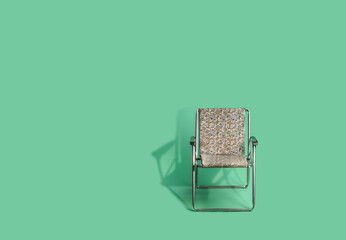 a folding chair from the seventies for the beach on a green background.