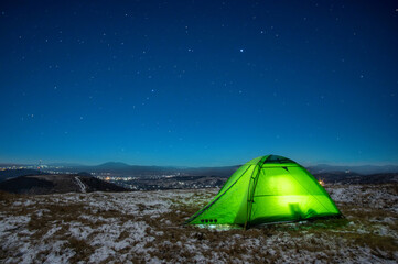 Night at the top of the mountain in a tent in winter against the background of the starry sky