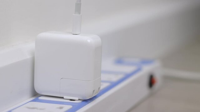 Close up male hand put on the Electric adapter smartphone or laptop plug. Electrical wires and power strips in the house