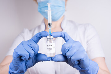 A woman doctor holding a vial with covid-19 vaccine and syringe on a white background.