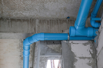 blue plastic water tube install on concrete white wall for building restroom in house site. fixing...