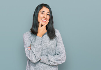 Beautiful asian young woman wearing casual clothes looking confident at the camera smiling with crossed arms and hand raised on chin. thinking positive.