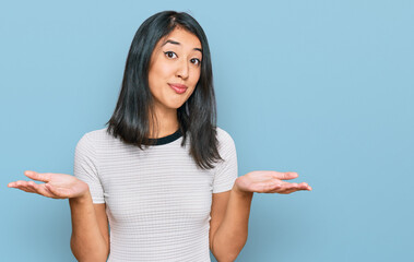 Beautiful asian young woman wearing casual white t shirt clueless and confused expression with arms...