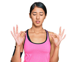 Beautiful asian young sport woman wearing sportswear and arm band relax and smiling with eyes closed doing meditation gesture with fingers. yoga concept.