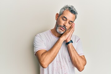 Middle age grey-haired man wearing casual clothes sleeping tired dreaming and posing with hands together while smiling with closed eyes.