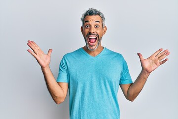 Fototapeta premium Middle age grey-haired man wearing casual clothes celebrating crazy and amazed for success with arms raised and open eyes screaming excited. winner concept