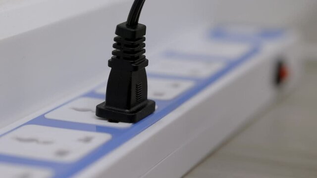 Hand holding Electric plug put on multiple socket. Electrical equipment, electrical wires and power strips in the house. Earth Hour saving electrical energy.
