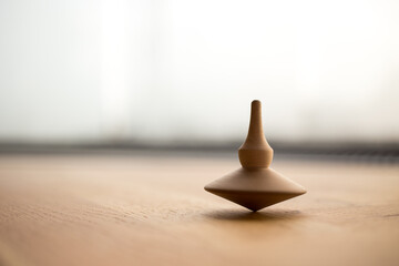 wooden Spinning top in action on wooden flor, rotating totem in motion - obrazy, fototapety, plakaty