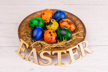 
Easter colorful eggs in a plate on a white background.
Easter inscription in wooden letters.