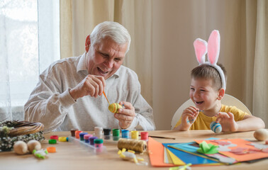 Happy elderly man granfather preparing for Easter with grandson. Portrait of smiling boy with bunny...