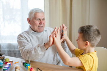 Happy elderly man grandfather preparing for Easter with grandson. Portrait of smiling boy with...