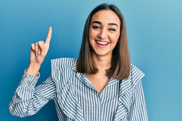 Young brunette student girl pointing up with finger smiling and laughing hard out loud because funny crazy joke.