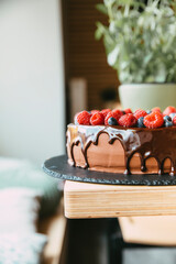 Rich chocolate layer cake with raspberries and a melted chocolate drip on top 