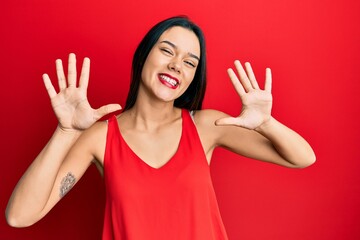 Young hispanic girl wearing casual style with sleeveless shirt showing and pointing up with fingers number ten while smiling confident and happy.
