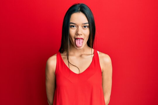 Young hispanic girl wearing casual style with sleeveless shirt sticking tongue out happy with funny expression. emotion concept.