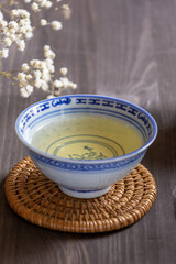 Top view of a cup of Chinese tea with white flowers, with selective focus, on dark table, in vertical, with copy space