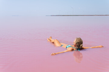 Woman swimming in salt plains waters colored with pink algae, Kherson oblast of Ukraine
