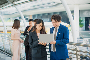 Obraz premium Businessman and businesswoman conversation using laptop computer,working and communicating,business team discussion,meeting together outside office,work planning strategy marketing analysis accounting