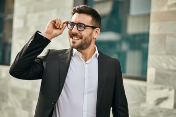 Young hispanic businessman smiling happy standing at the city.
