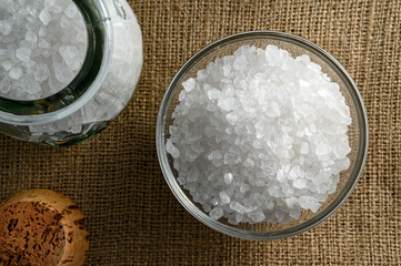 Glass jar and bowl of sea salt on sackcloth