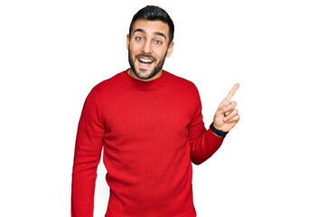 Fototapeta premium Young hispanic man wearing casual clothes with a big smile on face, pointing with hand finger to the side looking at the camera.