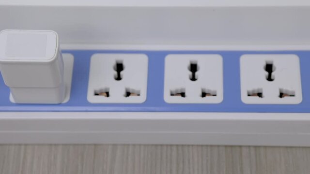 Hand holding Electric plug put on multiple socket. Electrical equipment, electrical wires and power strips in the house. Earth Hour saving electrical energy.
