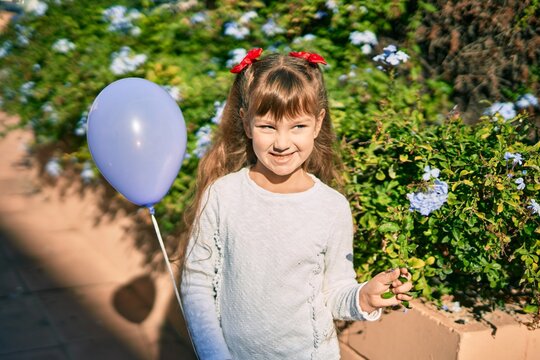 Adorable caucasian child girl  smiling happy playing with ballon at the park.