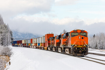 Winter scene of a locomotive pulling a freight train close to Whitefish, Montana with exhaust...