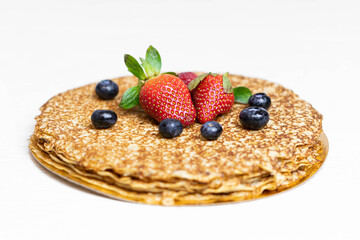 Ripe juicy strawberries and blueberries lie on a delicious pancake. Russian cuisine national dish bliny with fresh berries. Shrovetide