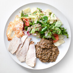 Beans, baked chicken wing, salad omelette on a plate.