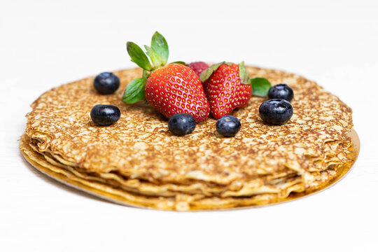 Ripe juicy strawberries and blueberries lie on a delicious pancake. Russian cuisine national dish bliny with fresh berries. Shrovetide