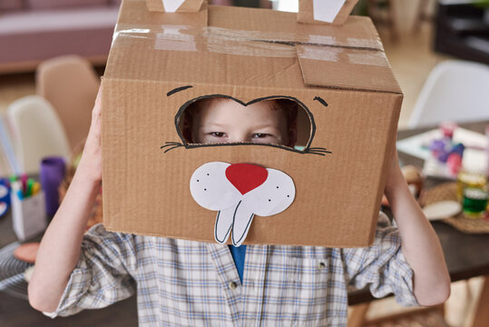 Portrait of happy boy in rabbit costume made of cardboard box smiling at camera