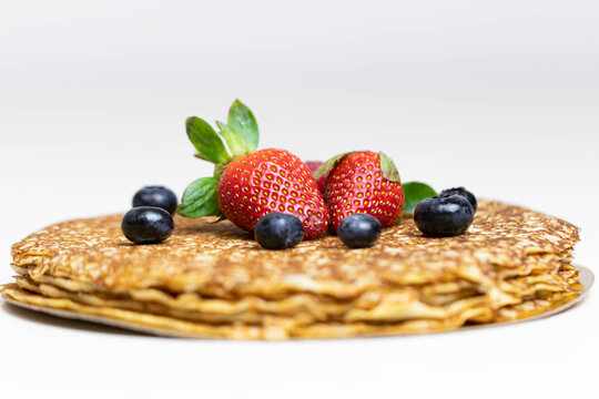 Ripe juicy strawberries and blueberries lie on a delicious pancake. Russian cuisine national dish bliny with fresh berries. Shrovetide