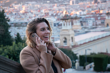 Young blonde woman with glasses laughs talking on the mobile in the city