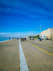 Thessaloniki Greece February 2, 2021:People are going for a walk on the beach on a bright day  wearing masks for protection from covid-19 