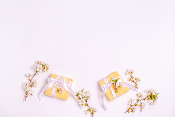 Blooming cherry branches with gift boxes on a white background and copy space. Flat lay, 8 March, Mother's Day, banner. View from above