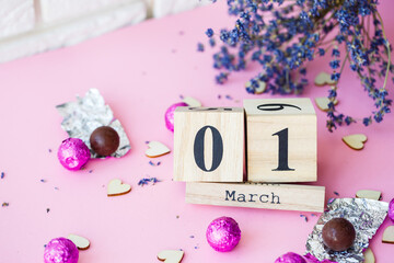 Wooden calendar with the date of March 1 on a pink background, a place for an inscription, The...