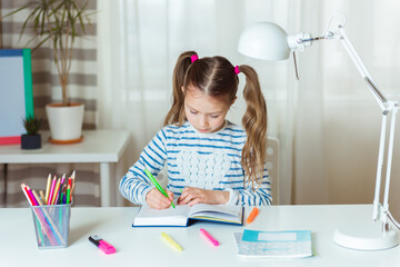 Pretty child girl writing notes in notebook daily planner, planning week, working or studying at...