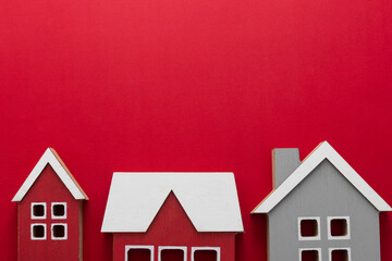 Wooden models of houses. Rent, buying or mortgage concept. Red background. Copy space.
