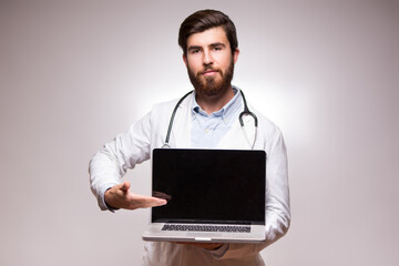 Young doctor with laptop on white background. Studio portrait.