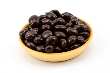 Wooden plate with a slide of raisins in chocolate, isolated on white background.