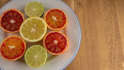 Juicy citrus fruits slices to make delicious juice on a white ceramic plate on a wooden table. top view, close up.