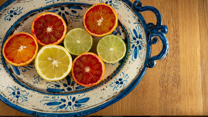 Juicy citrus fruits on a blue painted ceramic plate on a wooden table. top view, close up, top view.