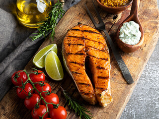 grilled steak fish salmon, trout in a old wood board, spices, rosemary, tomato, close up - 411289325