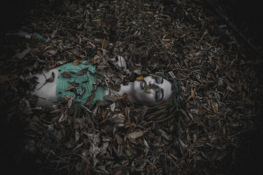 dead girl in autumn foliage wearing green and yellow robes
