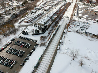 Parking lot filled with cars near commuter train transit at winter. Aerial view. The parking is...