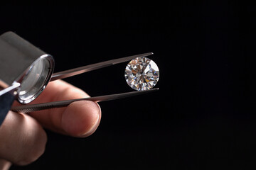 Large polished round cut diamond in hand close up front view. High quality photo
